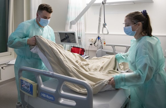 Ein Sanitaetssoldat und eine Pflegerin machen das Bett einer Covid-19 Patientin im Kantonsspital Fribourg HFR, am Donnerstag, 12. November 2020 in Fribourg. Angesichts der sanitaeren Lage und der Zuna ...