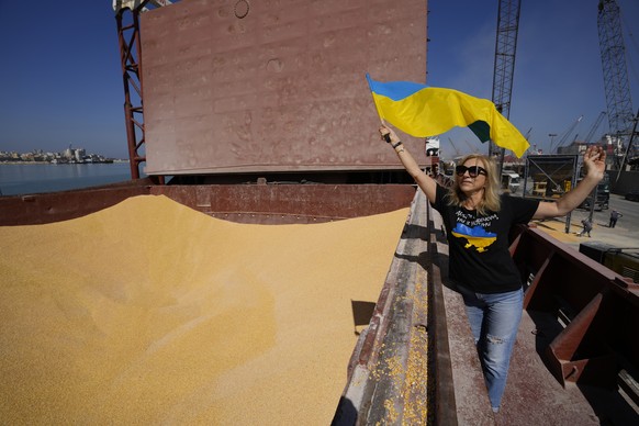 An Ukrainian woman who lives in Lebanon waves national Ukrainian flag as trucks being filled with Ukrainian corn from the ship AK Ambition, sailing under the flag of Panama at Tripoli seaport, in Trip ...