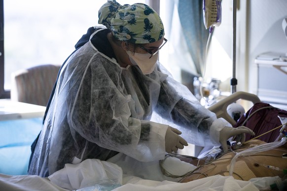 epa08992685 Registered Nurse Donna Bowes takes care of a Covid-19 patient in his ICU (Intensive care Unit) room at the Sharp Chula Vista Medical Center, amid coronavirus pandemic in Chula Vista, South ...