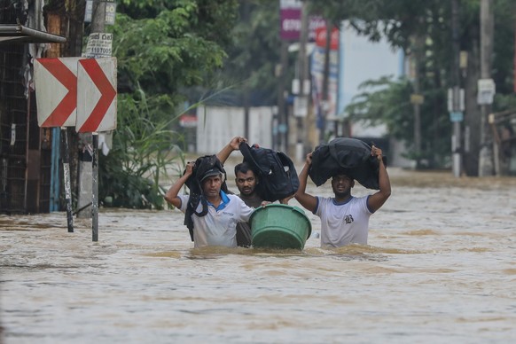 epaselect epa12556562 Sri Lankan flood victims wade through a flooded road during heavy rainfall in a suburb of Colombo, Sri Lanka, 29 November 2025. Many parts of the island have been inundated due t ...