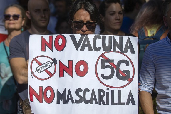 Demonstrators attend a protest against nationwide restrictions against COVID-19 in Madrid, Spain, Sunday, Aug. 16, 2020. A banner reads in Spanish &quot;No vaccine No 5G No mask&quot;. (AP Photo/Andrea Comas)
