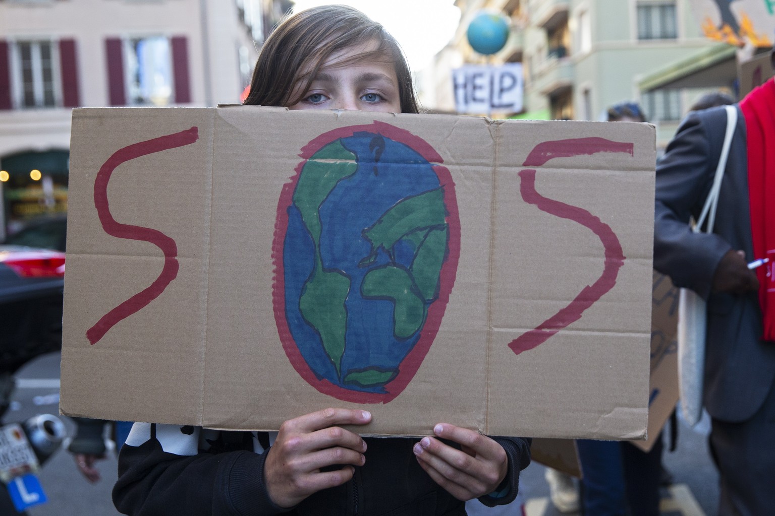 epa09539403 People holding placards attend a Global Climate Strike demonstration during the international strike day of Fridays For Future, in Geneva, Switzerland, 22 October 2021. Global Climate Stri ...