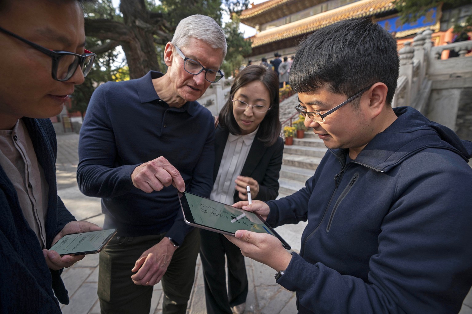 In this Oct. 10, 2018 photo released by China&#039;s Xinhua News Agency, Apple CEO Tim Cook, center, talks with Qu Zhangcai, left, and Liu Zhipeng, right, founders of the Xichuangzhu software app, dur ...