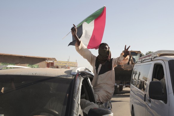 A Sudanese man gestures waving a Sudan flag following the reports that Sudan&#039;s army had entered the central city of Wad Madani and pushed out its paramilitary rivals the Rapid Support Forces (RSF ...