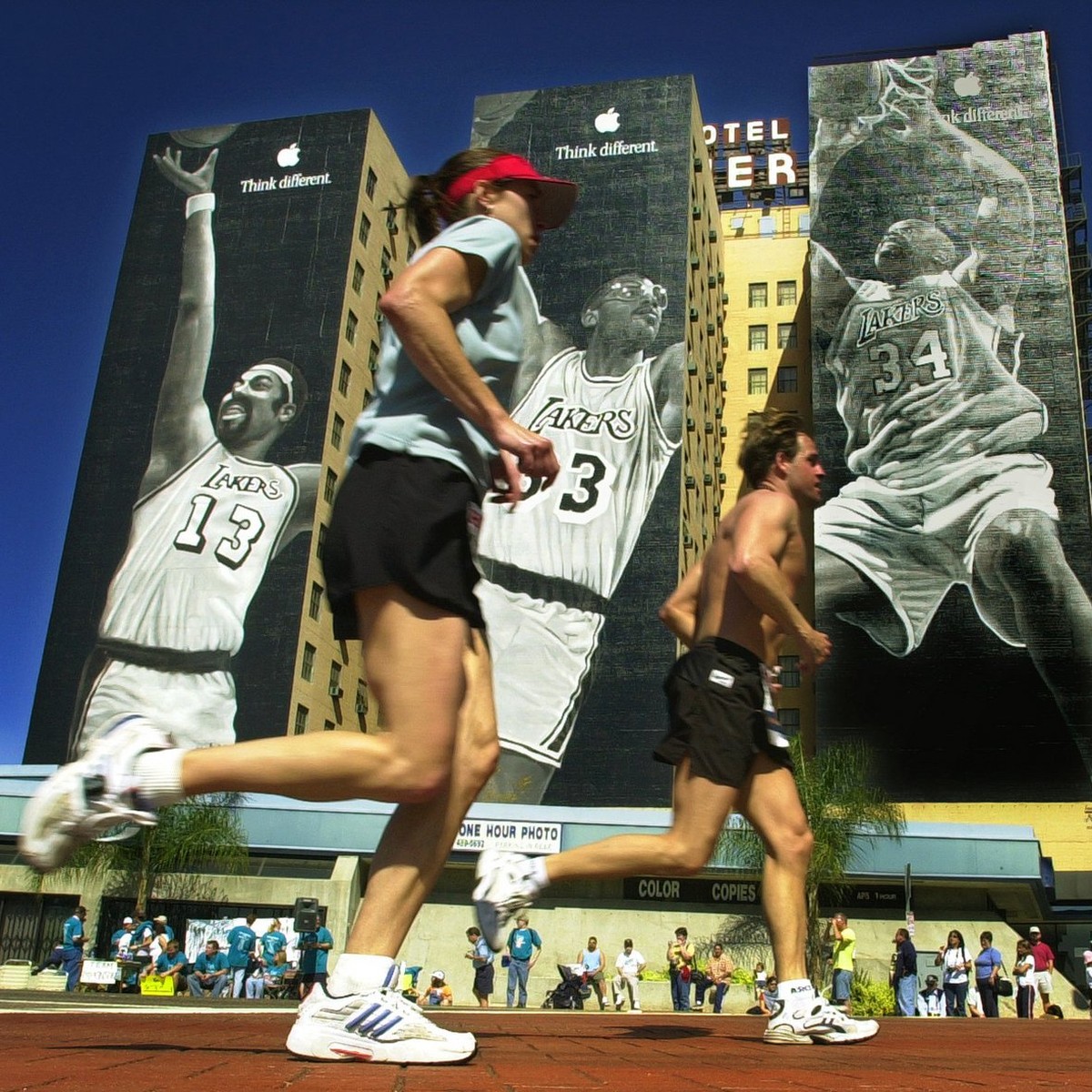 A pair of marathon runners pass by building-sized murals of Los Angeles Lakers stars, from left, Wilt Chamberlain, Kareem Abdul-Jabbar and Shaquille O'Neal on Olympic Boulevard as they near the f ...