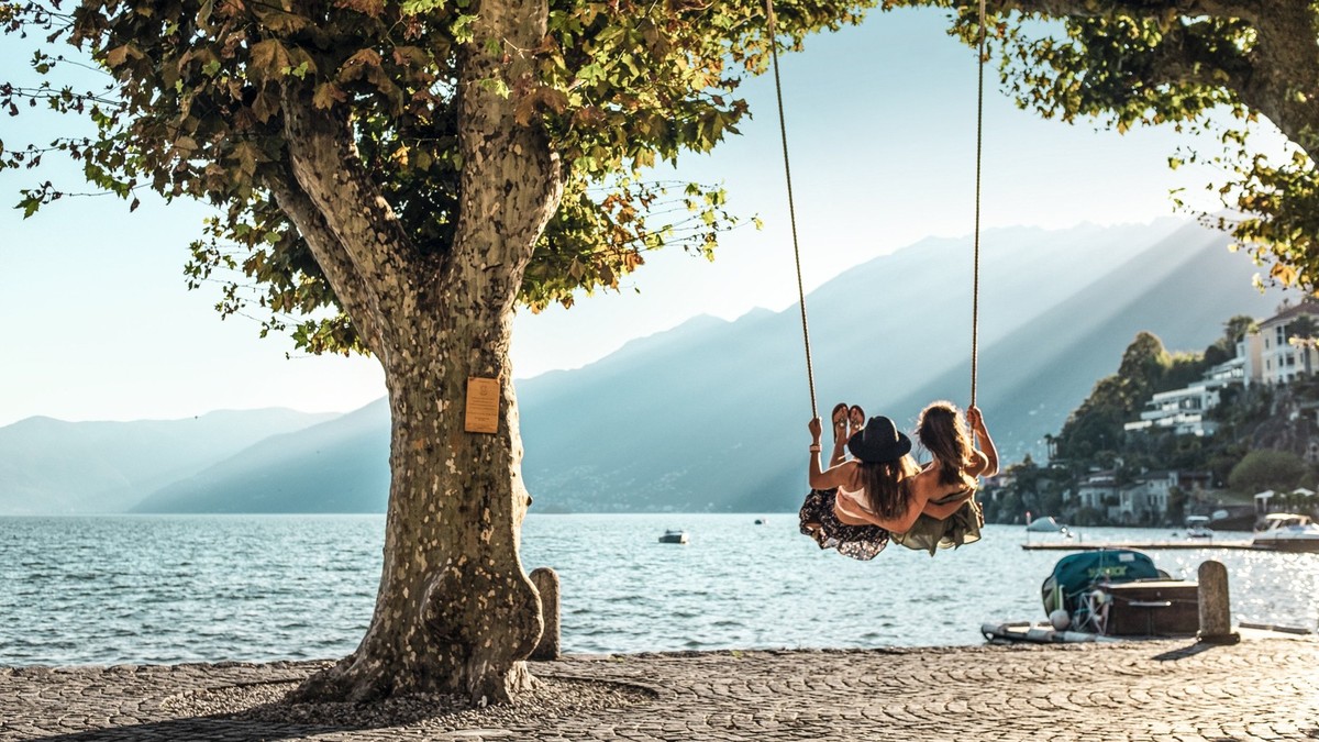 Zwei junge Frauen sitzen auf der Swing und schaukeln �ber den See in den Sonnenuntergang