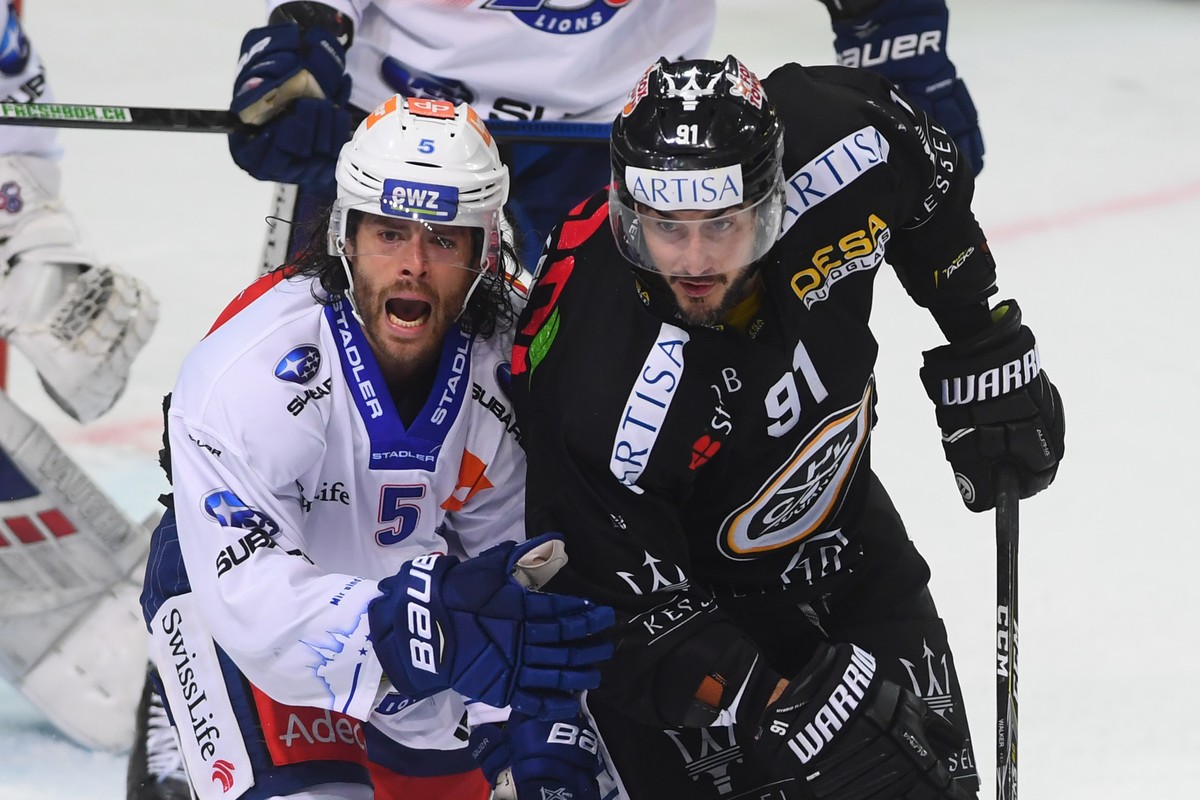 Zurich's player Severin Blindenbacher, left, fight for the puck with Lugano's player Julian Walker, right, during the preliminary round game of National League Swiss Championship 2018/19 bet ...