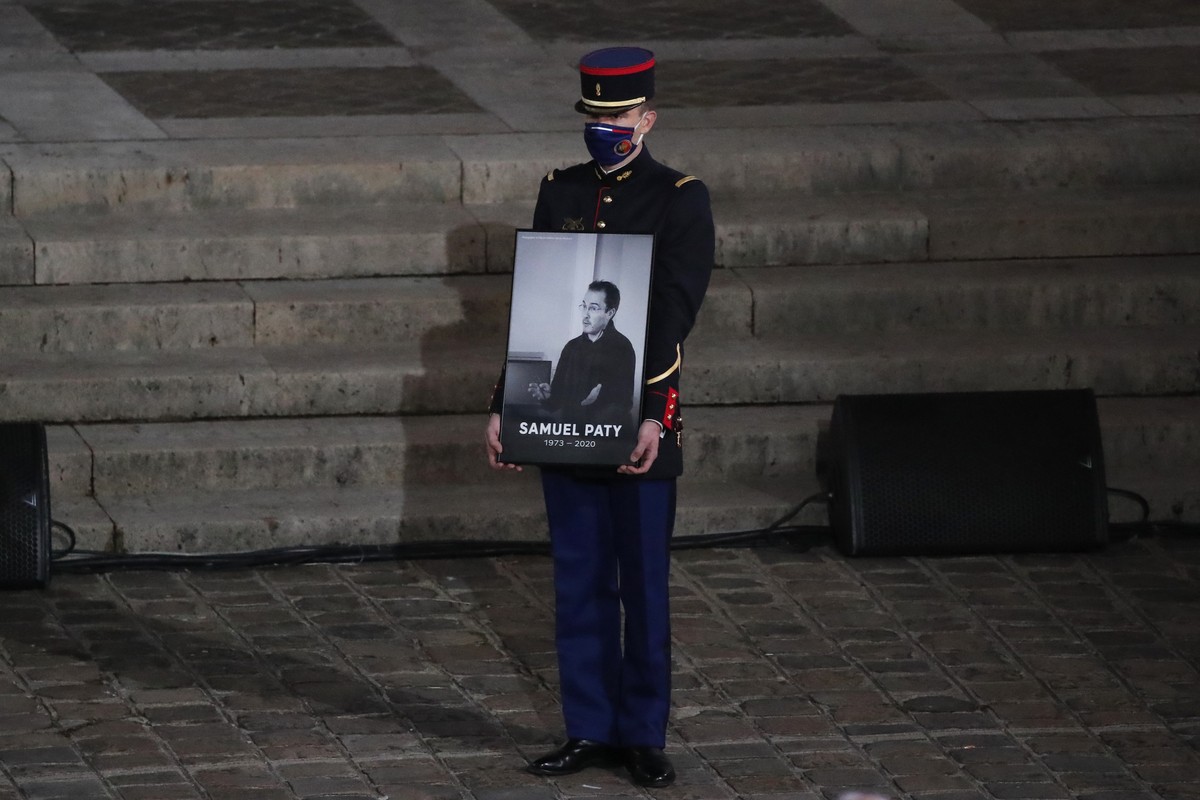 A Republican Guard holds a portrait of Samuel Paty in the courtyard of the Sorbonne university during a national memorial event, Wednesday, Oct. 21, 2020 in Paris. French history teacher Samuel Paty w ...