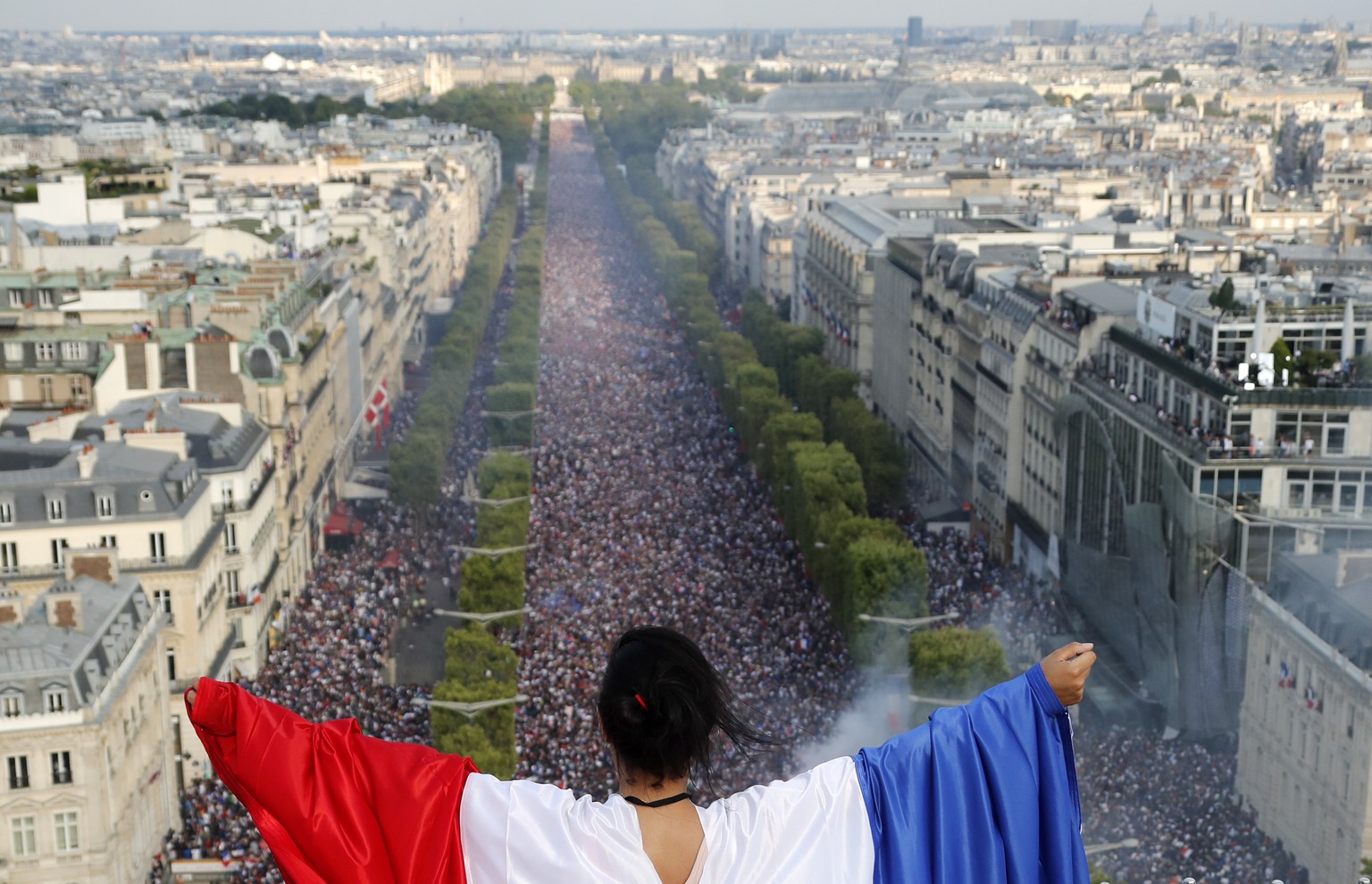 epa06891586 A French supporter waves a French flag as she celebrates after France won the 2018 World Cup at the Champs-Elysees venue during the FIFA World Cup 2018 final match between France and Croat ...