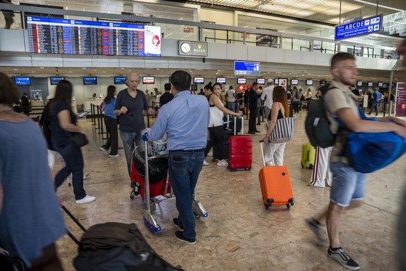 Travellers queue at Geneva Airport, in Geneva, Switzerland, Wednesday, June 15, 2022. After Swiss airspace was closed after a computer glitch with the air traffic control system grounded flights at th ...