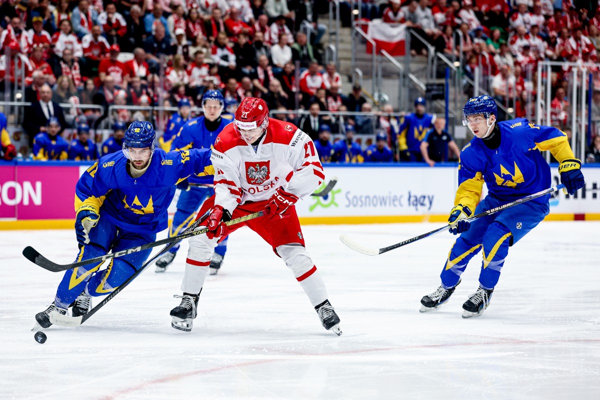 epa12928765 Poland's Kamil Walega (C) and Yevgen Fadyeyev (L) and Oleh Petrov (R) of Ukraine in action during the Division I Group A 2026 IIHF Ice Hockey World Championship match between Poland a ...