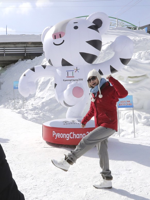 A visitor takes a souvenir photo with an official mascot of the 2018 Pyeongchang Olympic Winter Games, abwhite tiger Soohorang, at the Daegwanryung Snow festival in Pyeongchang, South Korea, Friday, F ...