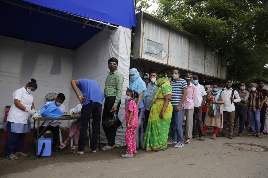 People stand in a queue to get the vaccine for COVID-19 during a special vaccination drive by the municipal corporation at a bus stand in Ahmedabad, India, Friday, Sept. 17, 2021. (AP Photo/Ajit Solan ...