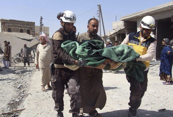 This photo provided by the Syrian Civil Defense group known as the White Helmets, shows members of the Syrian Civil Defense workers carrying a victim after a deadly airstrike hit a market killing seve ...