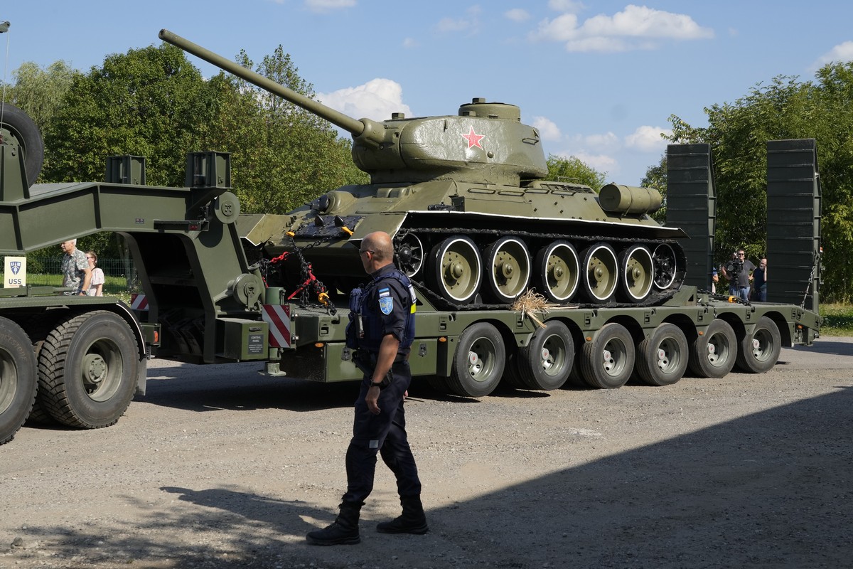 A policeman looks at a trailer transporting a Soviet T-34 tank which was installed as a monument in Narva, arriving to a military museum in Tallinn, Estonia, Tuesday, Aug. 16, 2022. Estonia's gov ...