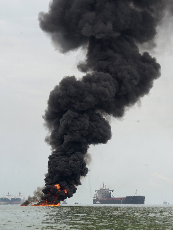 epa06638255 A black smoke cloud billows from a burned oil spill at the waters in Balikpapan, Indonesia, 31 March 2018. Two people reported dead believed to be fishermen as they were caught in the fire ...