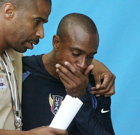 An unidentified man escorts Jon Drummond of the USA out of the stadium after he was disqualified for a false start in the second round of the men&#039;s 100-meter event, at the World Athletics Champio ...