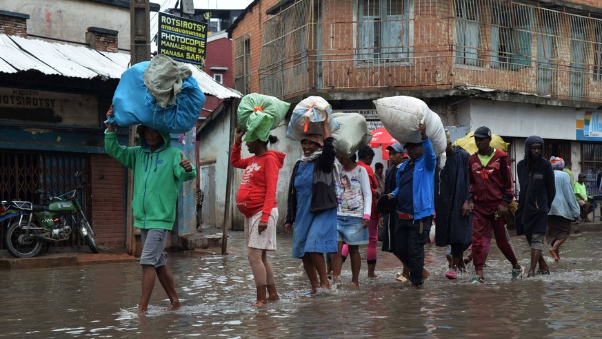 230126 -- ANTANANARIVO, Jan. 26, 2023 -- People walk on a flooded road in Antananarivo, Madagascar, on Jan. 25, 2023. The death toll has risen to 16 with 19 people still missing after the strong tropi ...