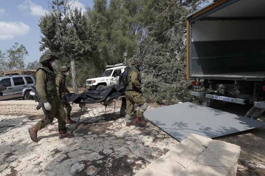 epa10911406 Israeli soldiers take the bodies of Israelis killed in Kfar Aza kibbutz near the border with Gaza, 10 October 2023. More than 900 people have been killed, around 150 were taken as hostages ...