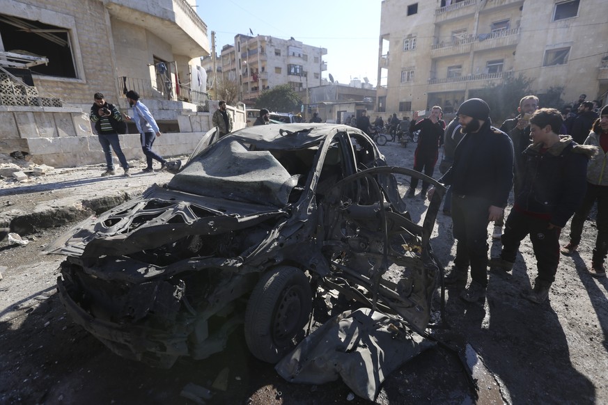 People look at a car destoyed by airstrikes in the village of village of Binnish, in Idlib province, Syria, Saturday, Jan. 11, 2020. Syrian government warplanes struck several rebel-held areas in the  ...