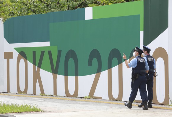 Police officers walk by posters to promote Tokyo 2020 Olympics in Tokyo, Wednesday, July 14, 2021. The Olympic Games are scheduled to begin on July 23. (AP Photo/Koji Sasahara)