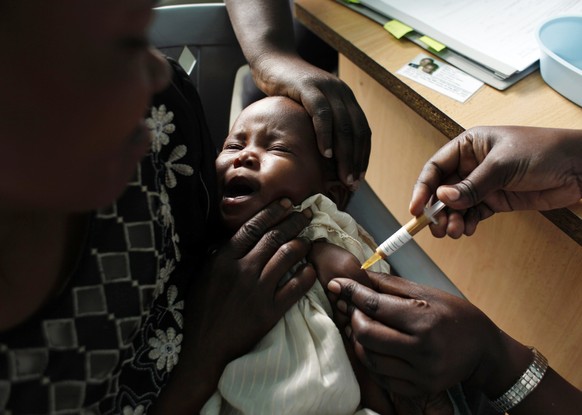 FILE - A mother holds her baby receiving a new malaria vaccine as part of a trial at the Walter Reed Project Research Center in Kombewa in Western Kenya on Oct. 30, 2009. Cameroon is beginning the wor ...