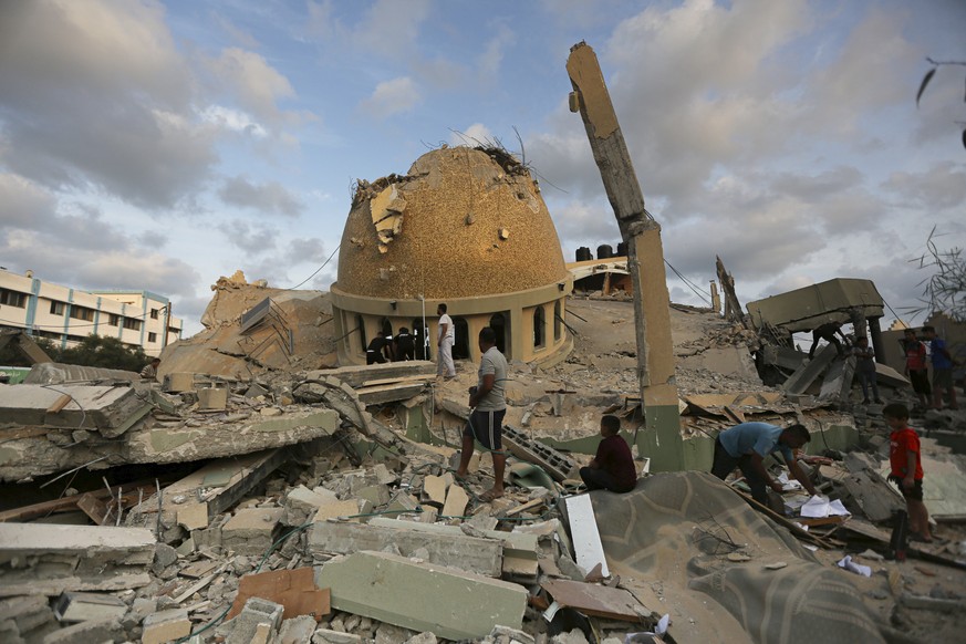 FILE - People stand outside a mosque destroyed in an Israeli air strike in Khan Younis, Gaza Strip, Sunday, Oct.8, 2023. As Israeli warplanes pummel Gaza to avenge the Hamas attack, Palestinians say t ...