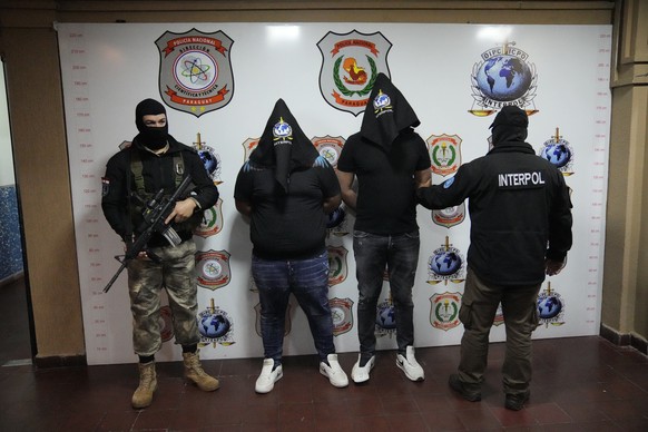 People identified by police as cousins with the same name, Giuseppe Giorgi, both from Italy, center, are shown with their faces covered to the press, by police at the Interpol Office in Asuncion, Para ...