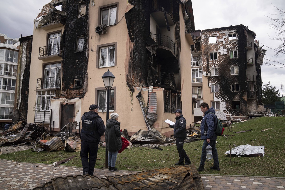 Oksana, second from left, and Yevhen, right, talk with Police officers next to their apartment building damaged by shelling in Irpin, in the outskirts of Kyiv, Ukraine, Monday, April 11, 2022. (AP Pho ...