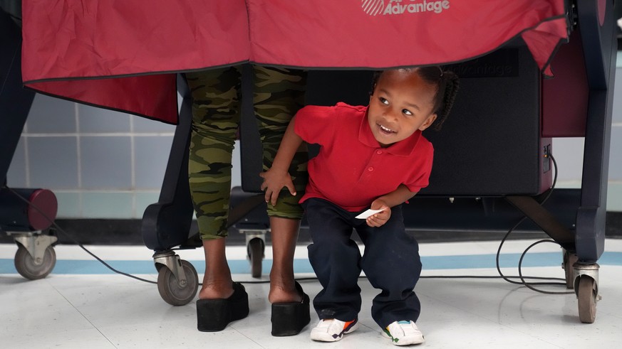 Kash Strong, 3, peeks out from under the curtain of a voting booth as his mother Sophia Amacker casts her vote on Election Day at the Martin Luther King Elementary School in the Lower Ninth Ward of Ne ...