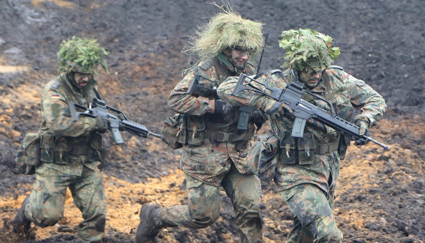 epa06256322 Armored infantrymen run in the mud during a media presentation for the annual Land Operation Exercise of the German Bundeswehr in Bergen, northern Germany, 10 October 2017. From 05 to 13 O ...