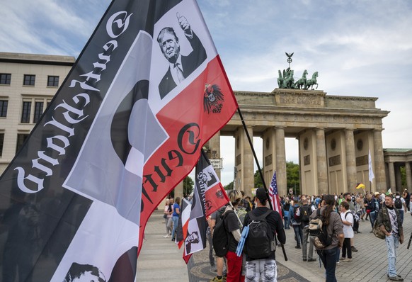 A protestor holds a flag of the German Reich with a picture of US President Donald Trump in front of the Brandenburg Gate before a demonstration against the coronavirus measures by the German Governme ...
