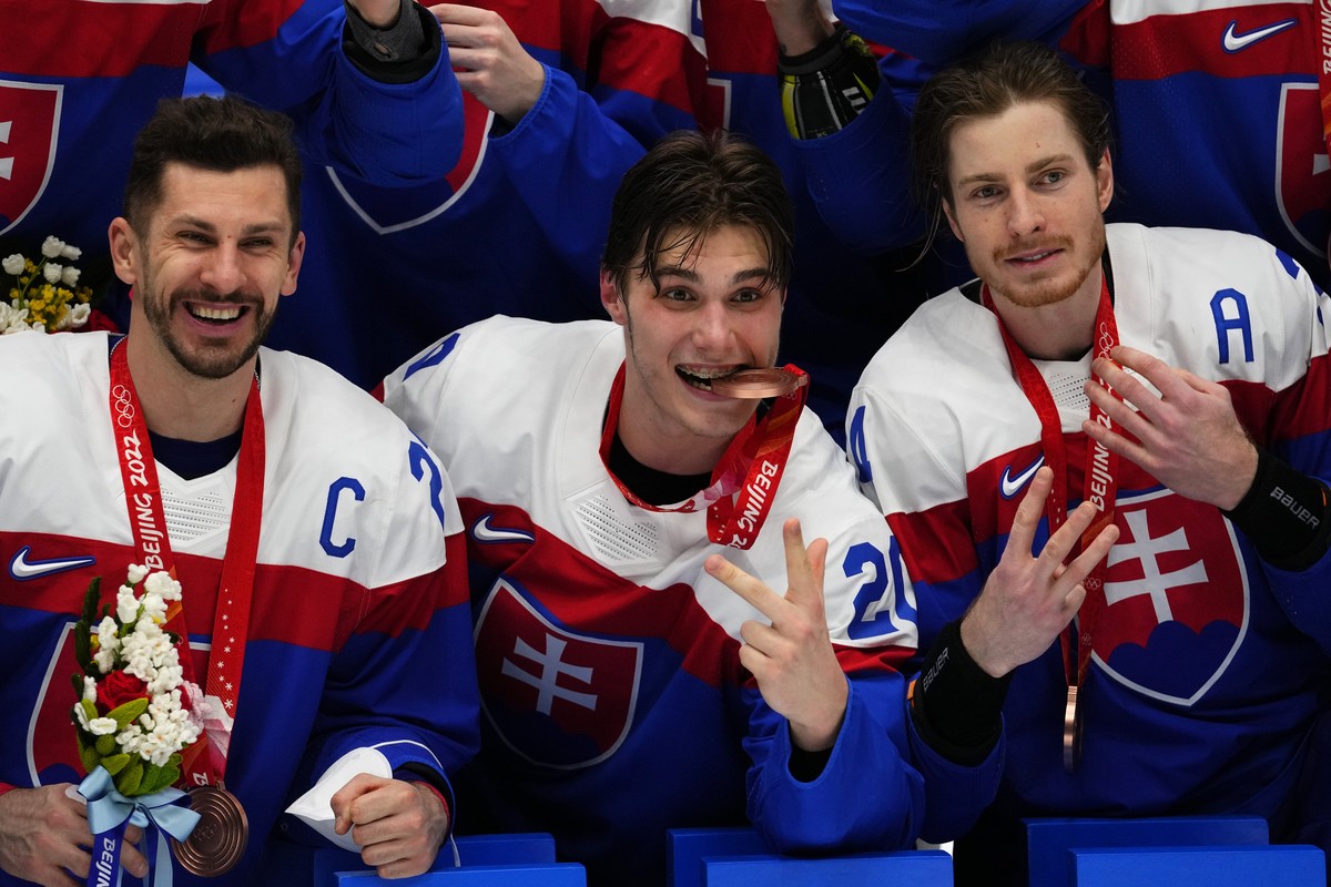 Slovakia's Marek Hrivik, from left, Slovakia's Juraj Slafkovsky, center, Slovakia's Peter Cehlarik pose with teammates after defeating Sweden in the men's bronze medal hockey game  ...