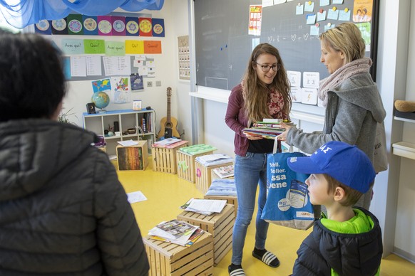 Stefanie Kuehni, Lehrerin, uebergibt einer Mutter das Schulmaterial fuer den kommenden Fernunterricht, am Dienstag, 17. Maerz 2020, an der Schule Duerrenroth. (KEYSTONE/Marcel Bieri )