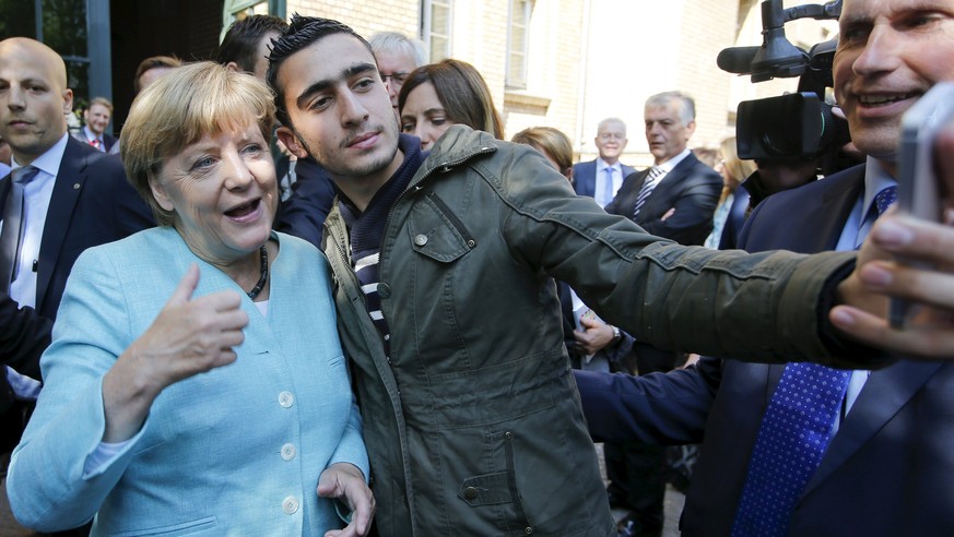 A migrant takes a selfie with German Chancellor Angela Merkel outside a refugee camp near the Federal Office for Migration and Refugees after registration at Berlin&#039;s Spandau district, Germany in ...