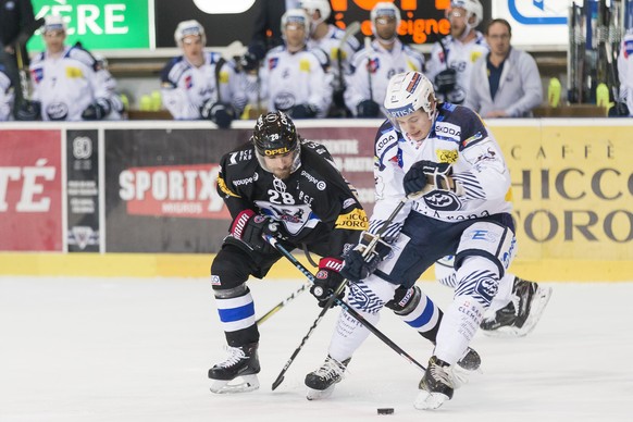 L&#039;attaquant fribourgeois Tristan Vauclair, gauche, lutte pour le puck avec le defenseur tessinois Misha Moor, droite, lors du match du championnat suisse de hockey sur glace de National League en ...