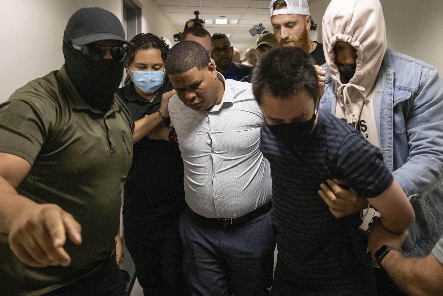 A Dominican man, center, and an activist, right, are detained by plain clothes officers with Immigration and Customs Enforcement after an immigration hearing at the immigration court inside the Jacob  ...
