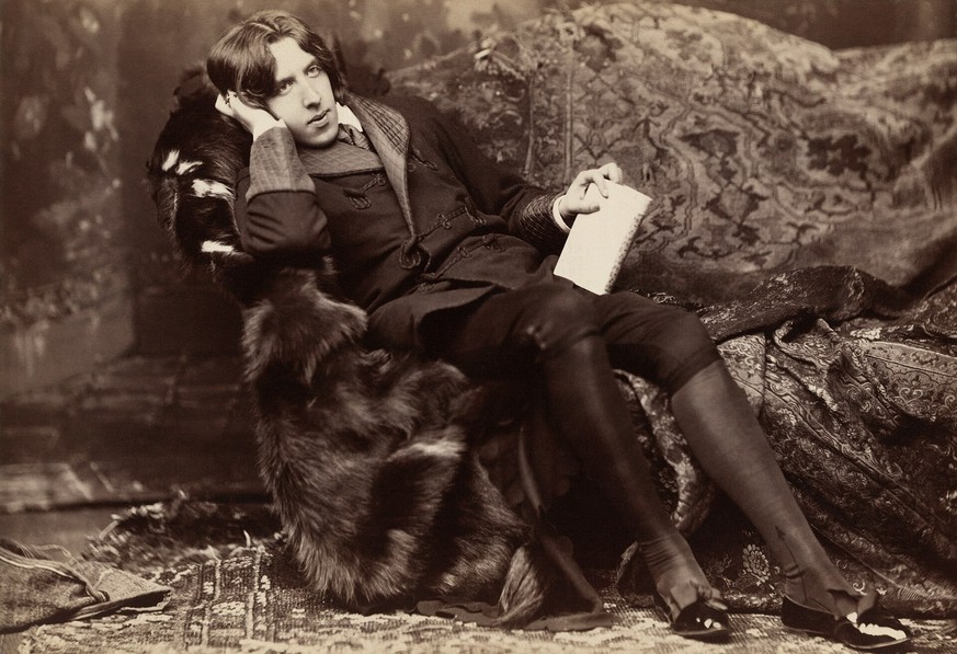 Oscar Wilde reclining with Poems, by Napoleon Sarony in New York in 1882. Wilde often liked to appear idle, though in fact he worked hard; by the late 1880s he was a father, an editor and a writer. 
h ...