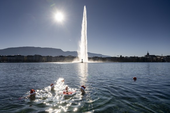 People swim with Santa hats in 8-degree water by the famous water fountain &quot;Le Jet d&#039;Eau&quot; in Lake Leman at Bains des Paquis on Christmas Eve, in Geneva, Switzerland, Sunday, December 24 ...