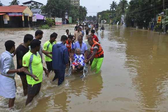 In this Thursday, Aug. 16, 2018 photo, an elderly woman is evacuated towards safer area in Thrissur, in the southern Indian state of Kerala. Rescuers used helicopters and boats on Friday to evacuate t ...