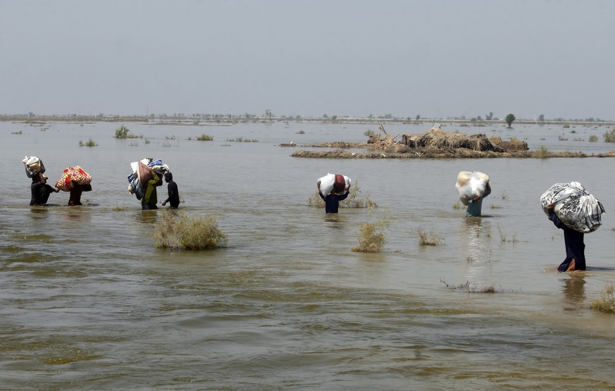 FILE - Victims of heavy flooding from monsoon rains carry relief aid through flood water in the Qambar Shahdadkot district of Sindh Province, Pakistan, Sept. 9, 2022. Scientists have said climate chan ...