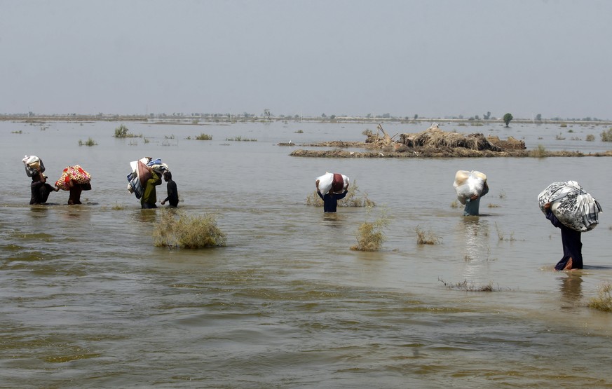 TILE - Victims of severe flooding from monsoon rains carry relief supplies through floodwaters in Qambar Shahdadkot district of Sindh province, Pakistan September 9, 2022. Scientists have said that climate change...