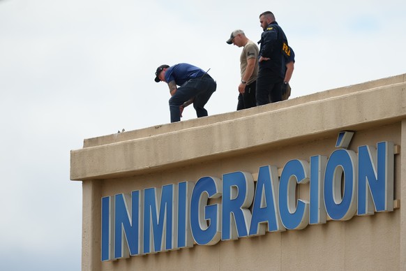 Law enforcement agents look around the roof of a building near the scene of a shooting at a U.S. Immigration and Customs Enforcement office in Dallas on Wednesday, Sept. 24, 2025. (AP Photo/Julio Cort ...