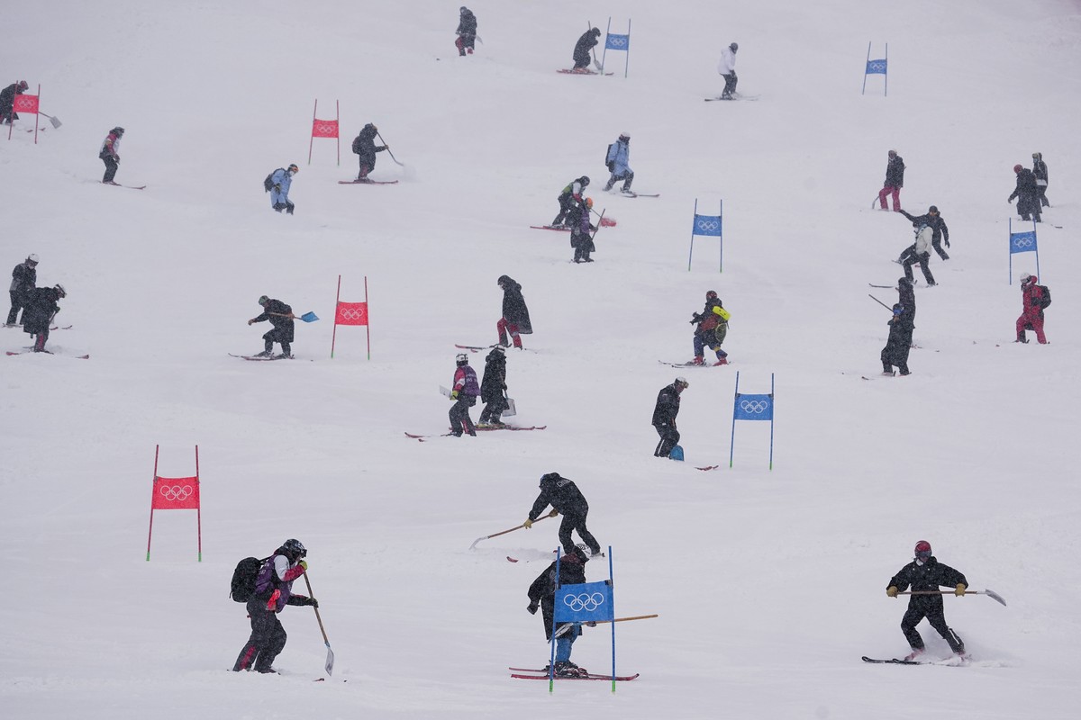 Workers clear snow from the course after the second run of the men's giant slalom was delayed due to a heavy snowfall at the 2022 Winter Olympics, Sunday, Feb. 13, 2022, in the Yanqing district o ...