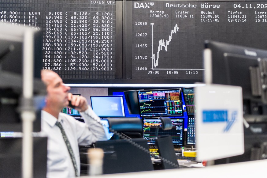 epa08797896 An electronic display shows the DAX chart, as a trader works in front of his computer screens at the trading floor of the Deutsche Boerse stock exchange, the morning following the US Presi ...