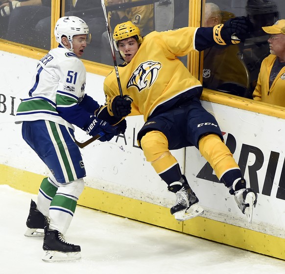 Vancouver Canucks defenseman Troy Stecher (51) checks Nashville Predators left wing Kevin Fiala (22), of Switzerland, into the boards during the third period of an NHL hockey game Thursday, Nov. 30, 2 ...