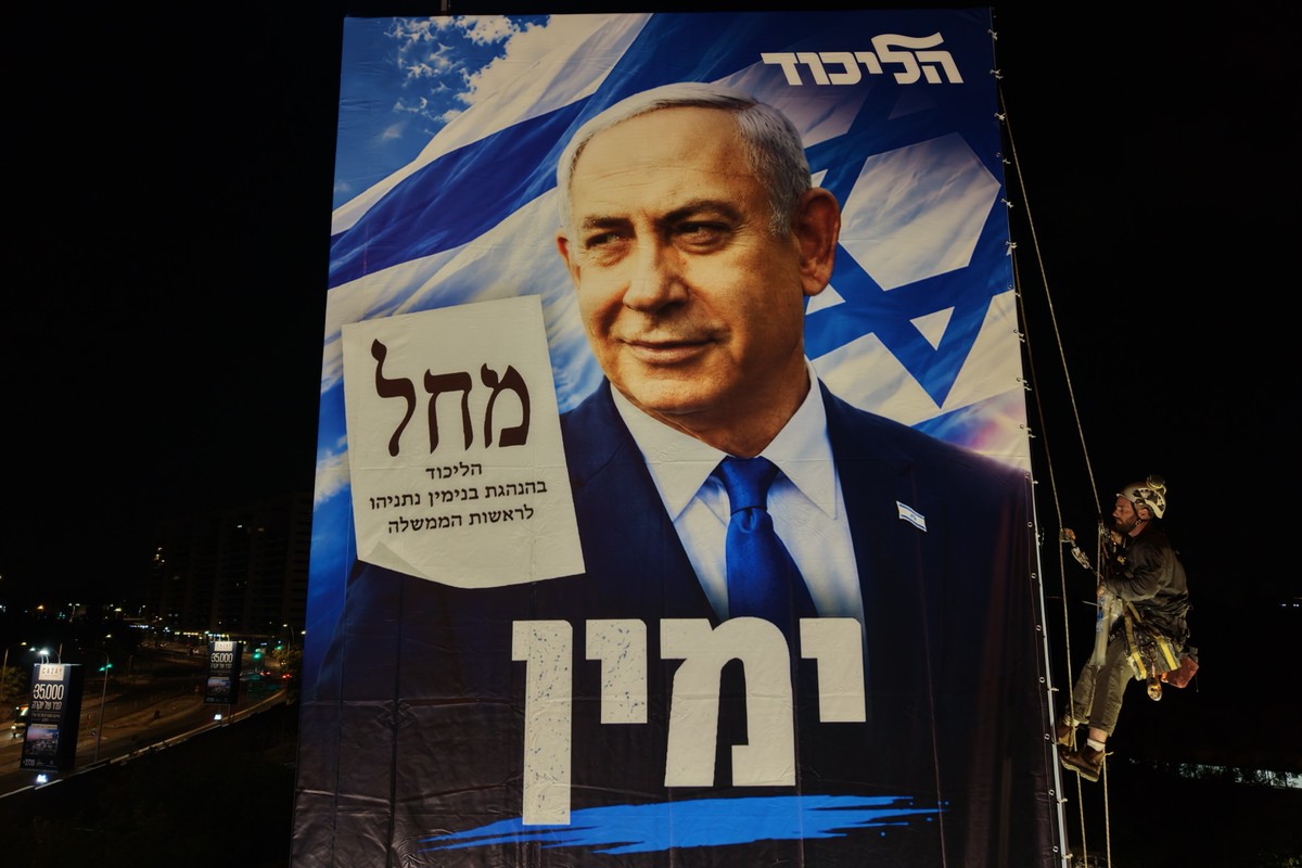 epa13312941 Rappelling workers install an election billboard featuring an image of Israeli Prime Minister Benjamin Netanyahu, and reading in Hebrew 'It's either the Right or Palestine,' ...