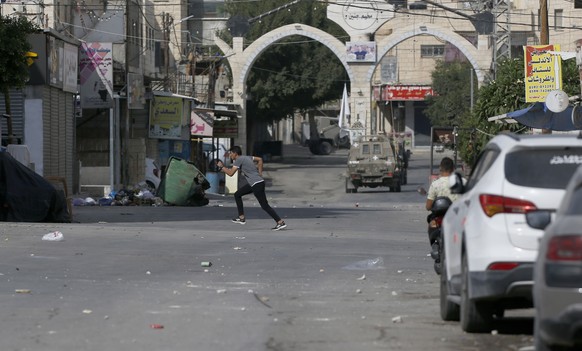 epa10230138 Palestinians watch Israeli troops during the operation of the Israeli army in the Jenin refugee camp, near the West Bank town of Jenin, October 08, 2022. According to the Palestinian Ministry of Health, two ...