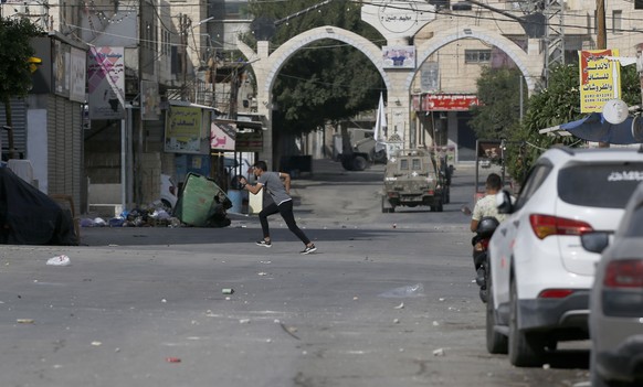 epa10230138 Palestinians watch Israeli troops during Israeli Army operation at Jenin refugee camp, near the West Bank city of Jenin, 08 October 2022. According to the Palestinian Health Ministry, two  ...