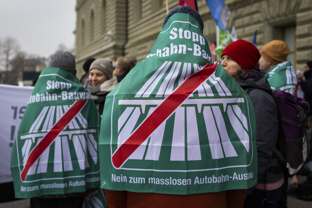 Unterstuetzer tragen Fahnen bei der Einreichung der Unterschriften fuer das Referendum "Stopp Autobahn-Bauwahn, Nein zum masslosen Autobahn-Ausbau", am Donnerstag, 11. Januar 2024 vor der Bu ...